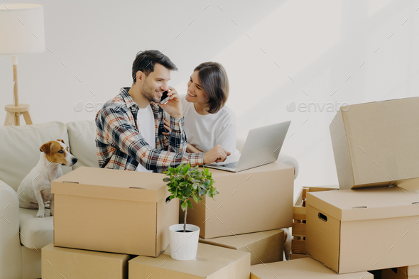 Happy husband and wife move in new bought house, buy furniture online, use modern technology