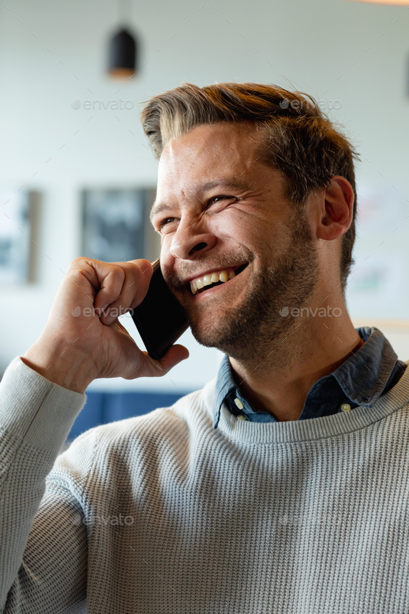 Happy caucasian mid adult businessman talking on smart phone in office - Stock Photo - Images