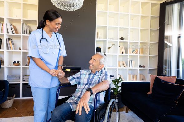 Biracial female health worker supporting caucasian senior man sitting on the wheelchair - Stock Photo - Images
