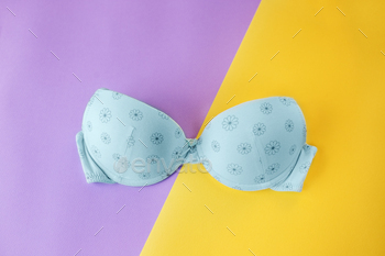 Blue bra on a yellow and purple background. Place for text. The concept of clothing