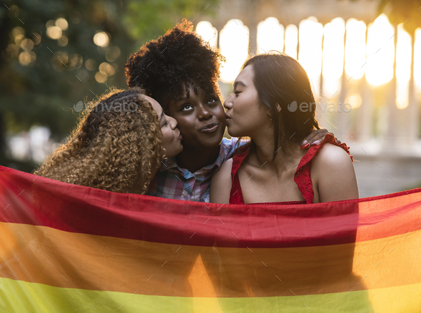 three friends kissing with gay pride flag, lgbt rainbow, happy women
