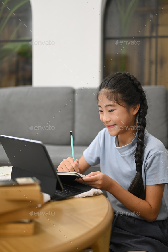 Smiling preteen girl having learning online at virtual class on laptop computer.