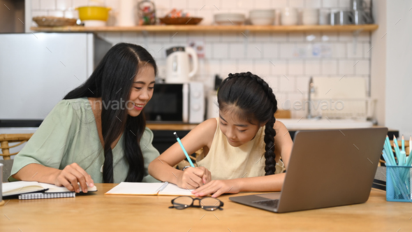 Asian mom helping her sweet daughter doing homework, learning online at virtual class.
