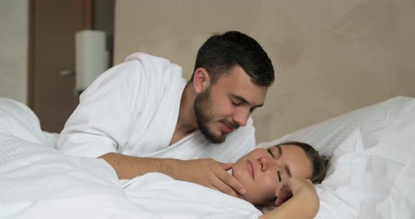 Man Kisses Girlfriend To Wake Up in Large Comfortable Bed alt