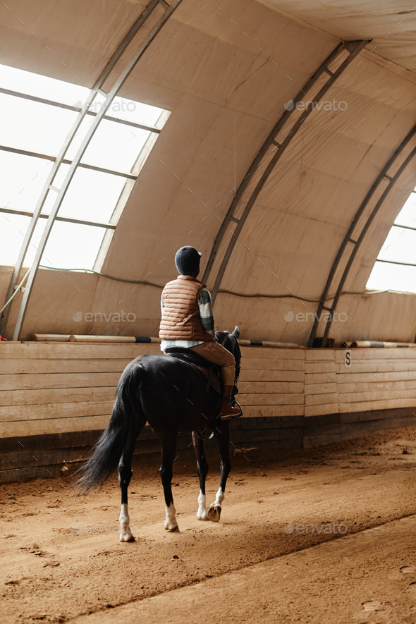 Woman Riding Horse in Covered Arena