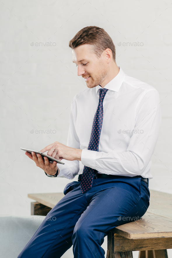 Pleased attractive young businessman checks email on portable pc