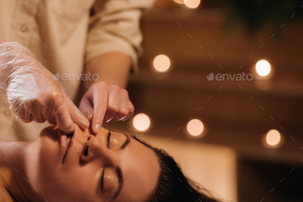A cosmetologist girl does a facial and neck massage to a girl in the office for skin elasticity