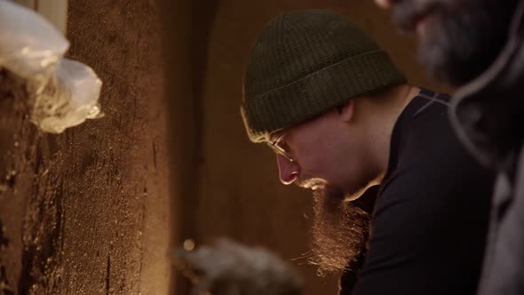 Two friends using clay to render walls in an old house, doing up a house alt