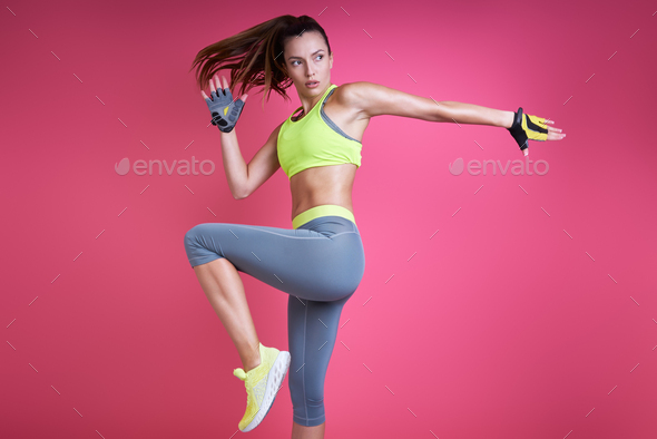 Confident young woman in sports clothing doing stretching