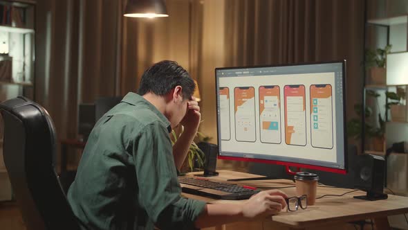 Tired Asian Male Mobile Application Developer Works With Graphics On His Personal Computer alt