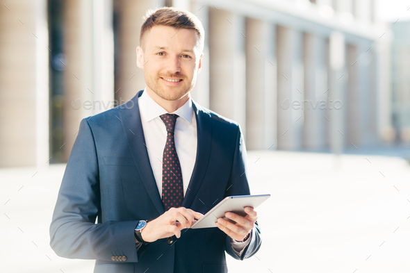 Cheerful successful young male executive manager, wears formal clothes, checks email box