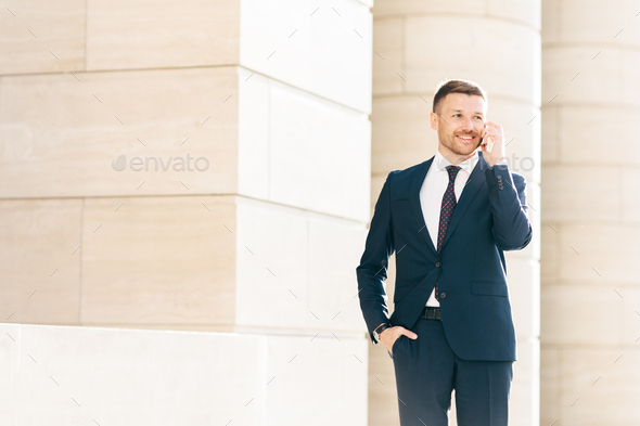 Attractive male CEO solves working issues with business partner during phone conversation