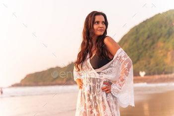 Portrait of a woman at sunset in a white dress enjoying the summer at the beach