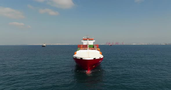 Container ship loaded with Shipping containers holding position at sea. alt