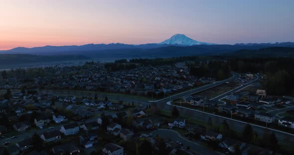 Wide orbiting aerial of a Puyallup neighborhood nestled under the looming presence of Mount Rainier alt