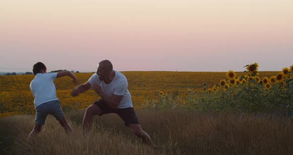 A Father And His Little Son Practice Boxing In The Field