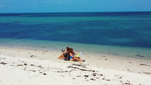 Female models best friends on marine coast beach wildlife by turquoise ocean and bright sand backgro alt