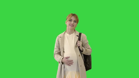 Happy Pregnant Girl Student Walking on a Green Screen, Chroma Key. alt