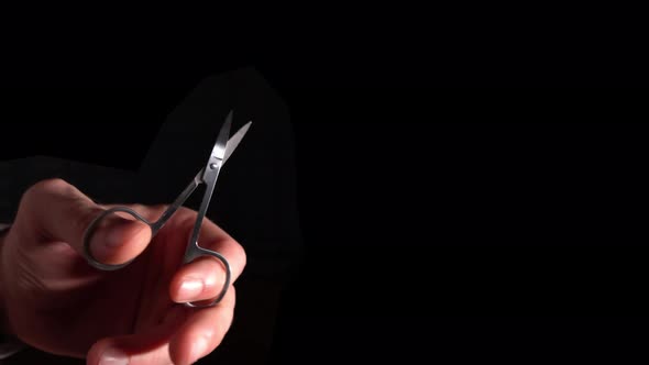 Small Scissors In Hand On Black Background