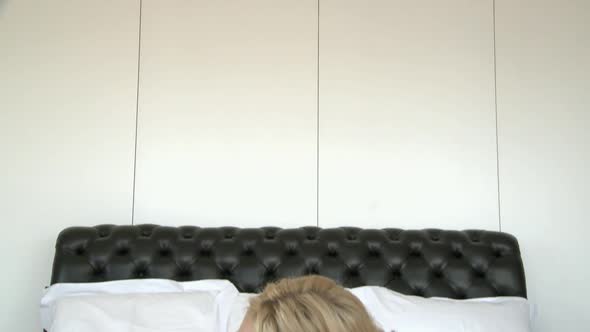 Blond woman lying on bed alt