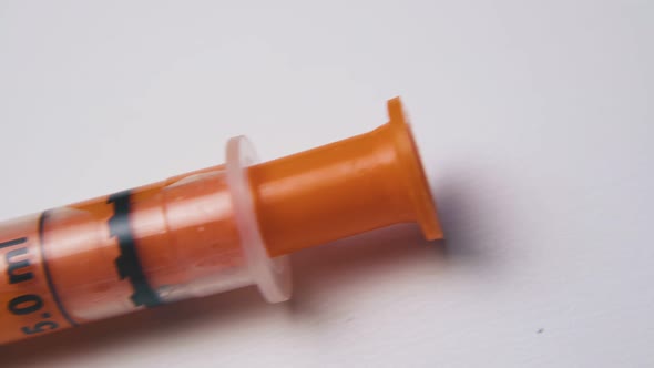 Syringe with Orange Element and Scale on White Background alt