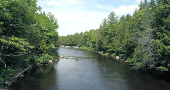 Flying above a river underneath blue skies at Tobey Falls near Willimantic, Maine. alt