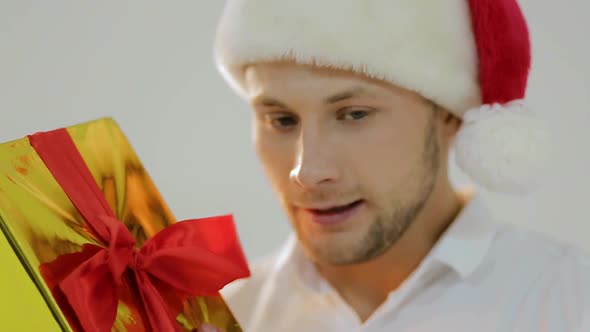 Man in Santa Hat Hold Christmas Present. The Morning Before Xmas. Delivery Christmas Gifts. Happy alt