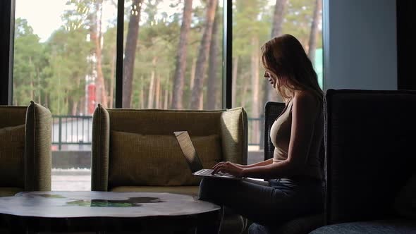 Woman Typing at Laptop Keyboard in Country House alt