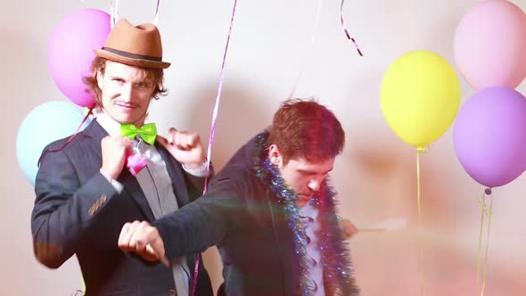 Two friends having fun dancing with props in photo booth alt