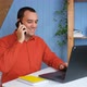 Smiling Young Business Man Professional Talking on Phone Using Laptop Sit at Home Office Desk - VideoHive Item for Sale