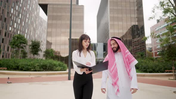 Businesswoman Discussing Papers with Arab Client alt