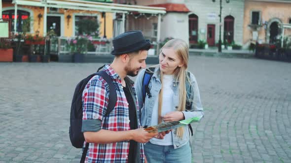 Young Tourists Couple Finding Necessary Destination on Map and Admiring Surroundings alt