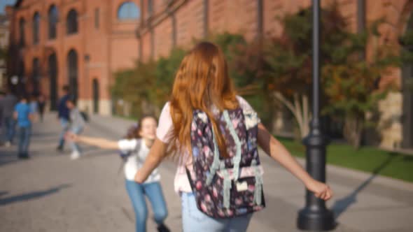 Happy Schoolgirls Meeting Outdoors and Embracing Happy To See Each Other alt