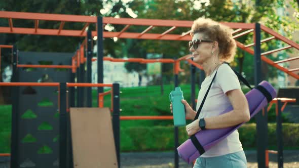 Mature Woman Going to Yoga Class Outdoors alt