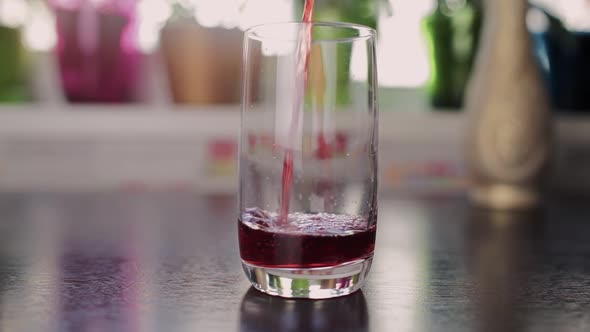 cherry juice is poured into a glass in the kitchen