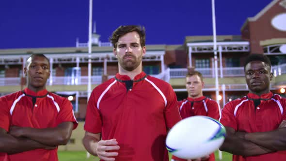 Male rugby players with rugby ball and arms crossed standing in stadium 4k