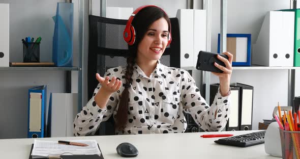 Businesswoman in Red Headphones Shooting Video on Smartphone in Modern Office