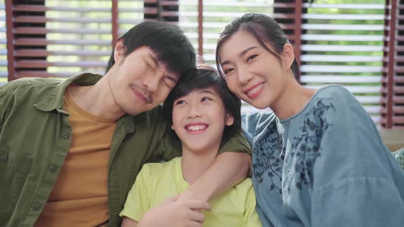 Portrait of Asian sweet family  sitting and smiling in living room  son hug his parent with love alt