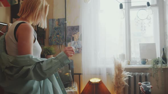 Young Woman Dancing and Smoking in front of Boyfriend at Home Party alt