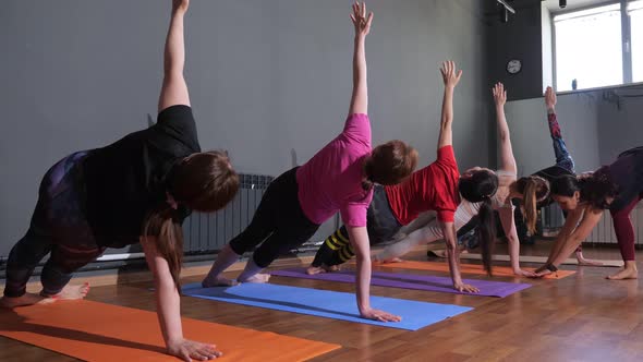 Young Woman Yoga Instructor Supervises the Performance of the Asana in a Group Lesson alt