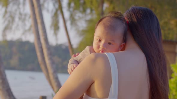 A young Asian mother is on the beach with her baby in summer time alt