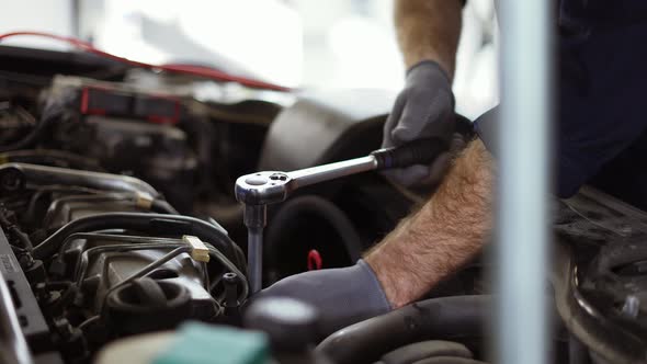 Car Mechanic Using Wrench to Repair the Engine in a Car Service Slow Motion alt