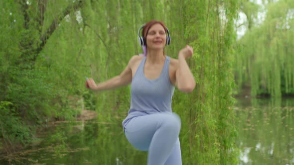 30s Woman in Headphones Jumping Doing Aerobics Exercises Outdoors alt