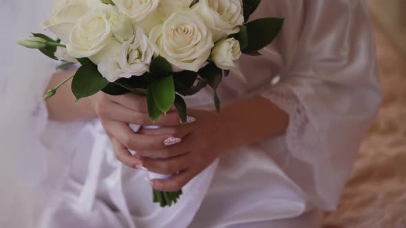 Woman Bride Holding Roses Bouquet in Hands. Female in Morning Wearing Robe Preparing for the Wedding