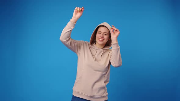 Happy Young Woman Dancing Against Blue Background