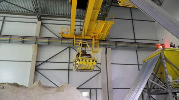 A Huge Radio-controlled Bucket, Grabs the Sand and Pours It Into a Large Sand Storage Hangar. alt