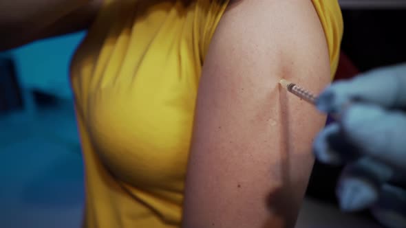 Injection with a syringe in the arm.  Doctor injects a coronavirus vaccine into a woman patient. alt