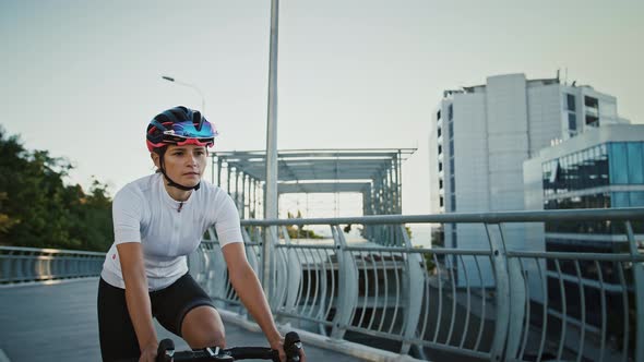 Female in Sportswear and Protective Helmet is Riding Trekking Bike Downhill Along Bridge Surrounded alt