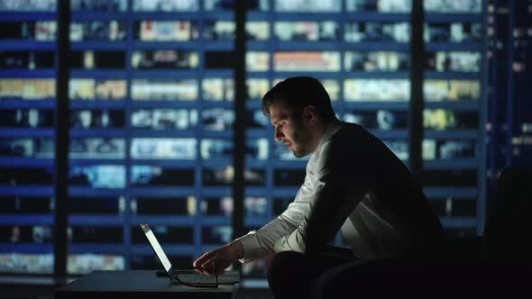 Tired Young Man Working on a Laptop Late Night in the Office alt