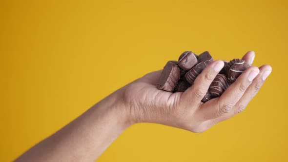 Holding Dark Chocolate Against Yellow Background alt